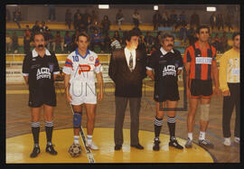 Elementos das equipas participantes em jogo de futebol, com  a equipa de arbitragem.